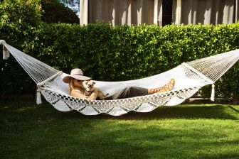 woman lying on hammock with a small dog