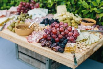 Closeup of wooden table with grapes, dates, nuts, olives and cheeses