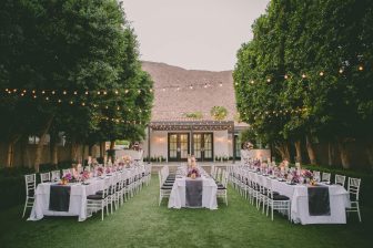 Lawn surrounded by trees and tables and chairs elegantly set