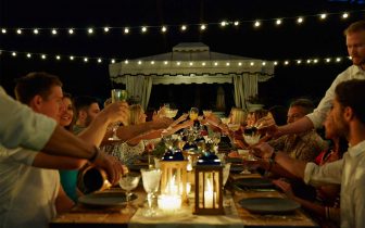 people sitting at long tables outdoors, raising glasses