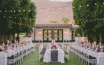 Looking into the Presidio Courtyard, with twinkle lights hanging over three banquet tables set for a wedding